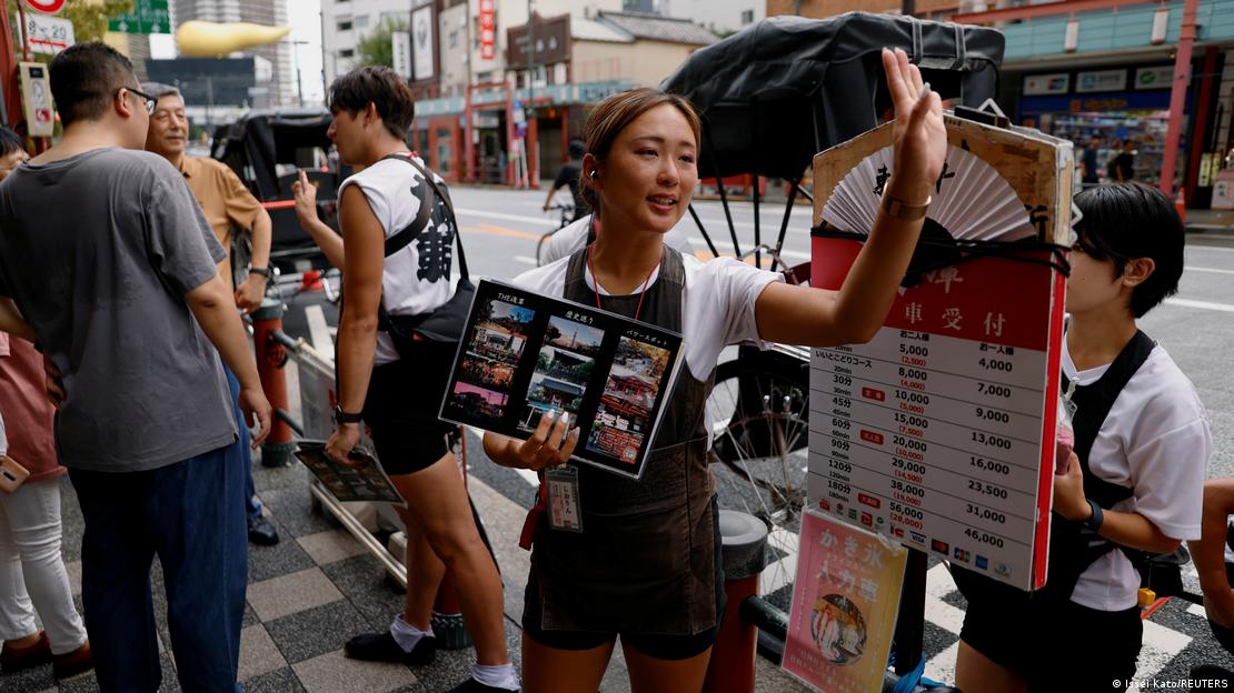 Una mujer invita a turistas a una visita guiada por el distrito de Asakusa, en Tokio.