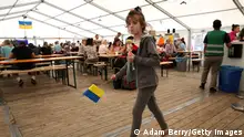 BERLIN, GERMANY - AUGUST 23: A child refugee from Ukraine holds a Ukrainian flag as she walks through a temporary welcome center tent outside the main train station (Hauptbahnhof) on August 23, 2022 in Berlin, Germany. The following day, August 24, is the 31st anniversary of when Ukraine's parliament vowed to separate from the Soviet Union in 1991 but this year will also mark six months since the country's war with Russia began. Ahead of the holiday, the Ukrainian government is warning civilians against gathering in major cities. Over seven million refugees have left Ukraine since the start of Russia's invasion in the largest mass population displacement in Europe since World War II, with an estimated 900,000 of them seeking permanent or temporary residence in Germany. (Photo by Adam Berry/Getty Images) (Photo by Adam Berry/Getty Images)