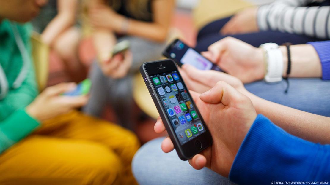 Mãos de jovem mexendo em celulares