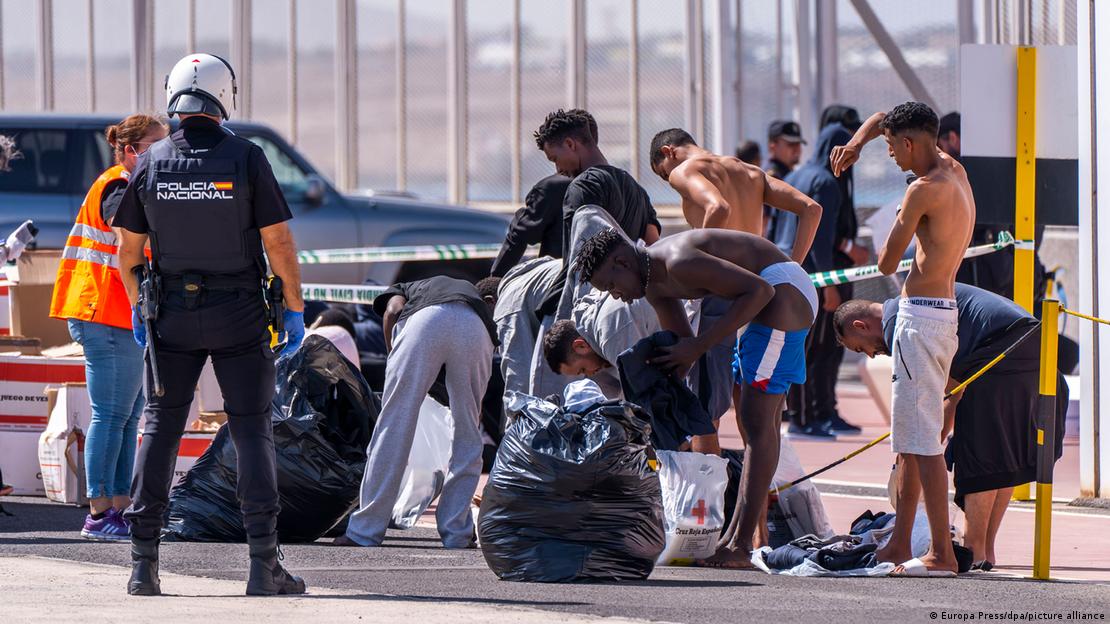 Migrantët e marrë nga varkat në Fuerteventura, Spanjë marrin veshje në prani të policëve