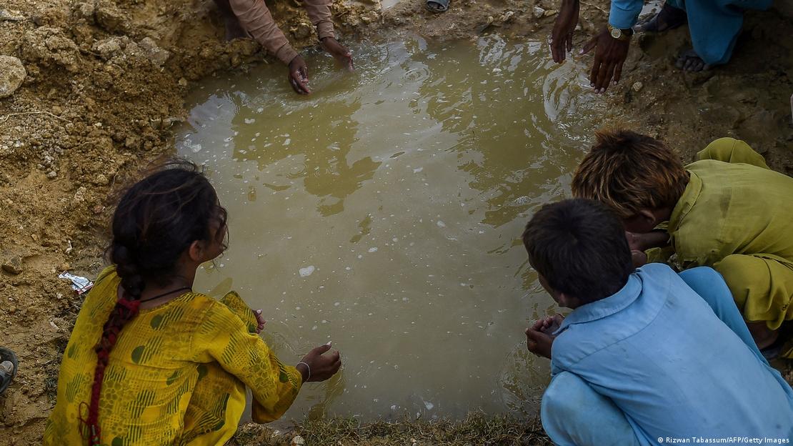 26 ستمبر 2022 کو لی گئی اس تصویر میں سندھ کے ضلع جامشورو میں سیلاب سے متاثرہ اور بے گھر ہونے والے افراد کے بچوں کو ایک عارضی کیمپ کے باہر جمع شدہ پانی کے گڑھے سے پانی پیتے ہوئے دیکھا جا سکتا ہے