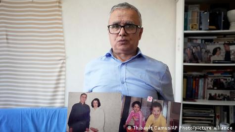 تقی رحمانی، همسر نرگس محمدی، با در دست داشتن عکس همسر و فرزندانش