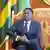 Faure Gnassingbé assis dans sur un canapé luxueux, avec un drapeau togolais derrière lui (archive de 2021)