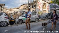People walk past the rubble of a building in Tel Aviv a day after it was hit by a rocket fired from the Gaza Strip.