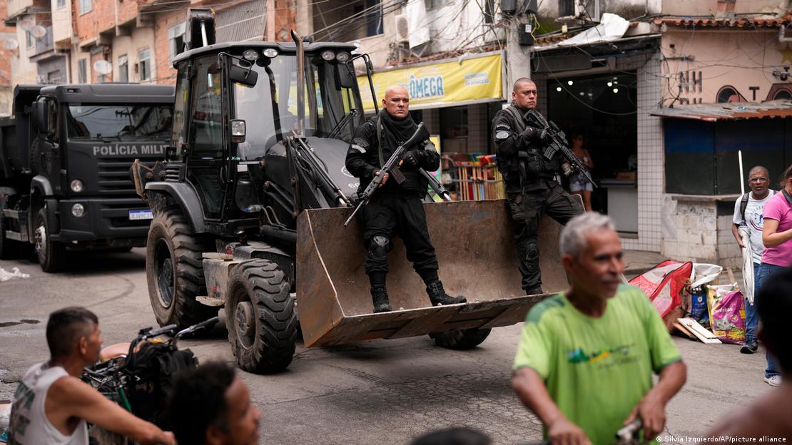 Dois policiais são conduzidos em cima de uma escavadeira em operação na favela da Maré, no Rio de Janeiro