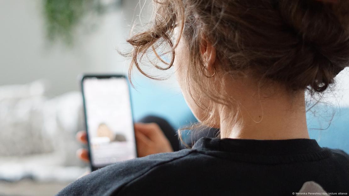 Elindeki cep telefonuna bakan genç bir kadın