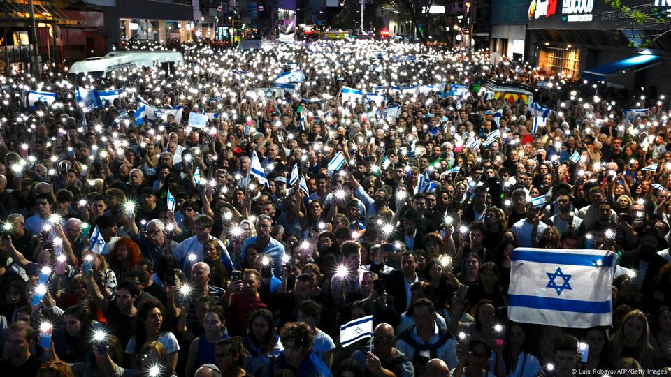 Una multitud con banderas de Israel y enciende las luces de sus celulares en señal de duelo.