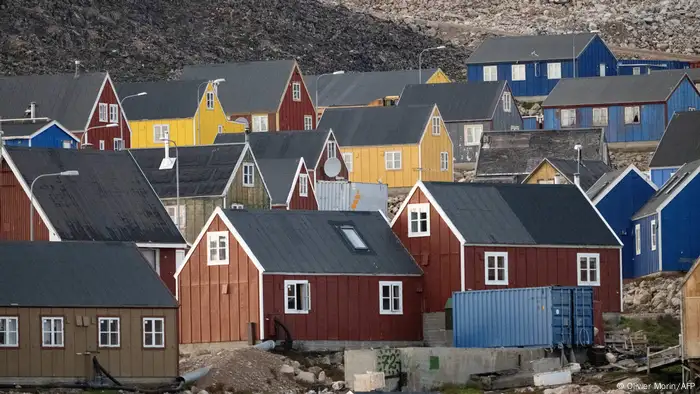 Blue, yellow, ocher and brown wooden houses stand close together in the remote village of Ittoqqortoormiit.