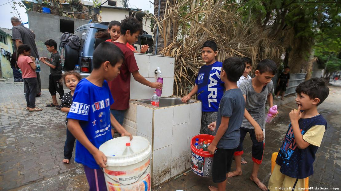 Crianças com balde pegando água em torneira