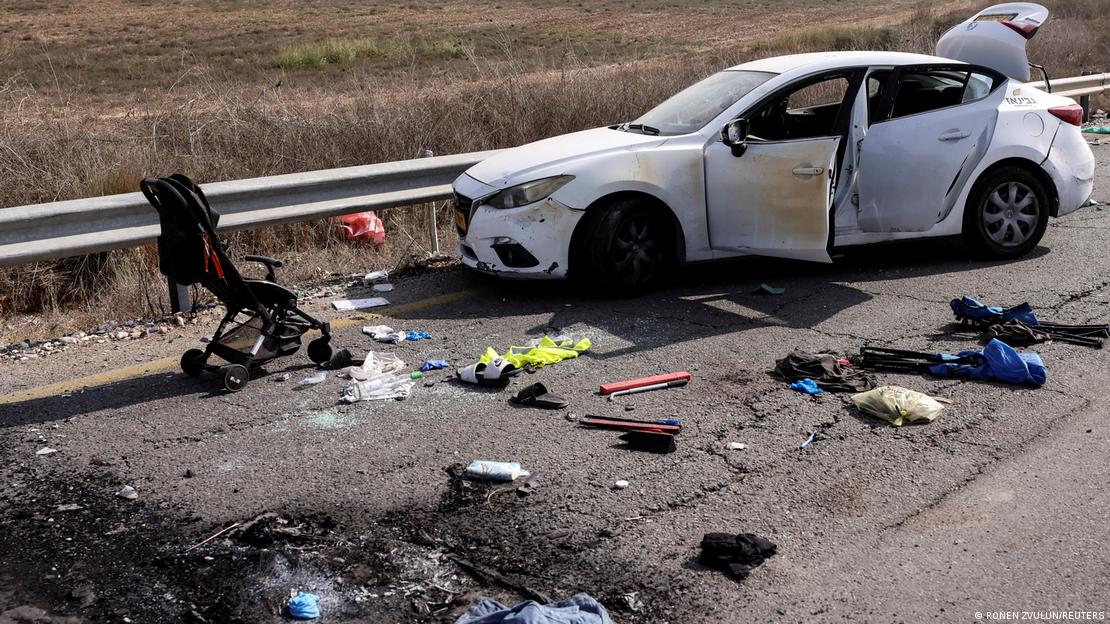 Pertences pessoais, incluindo um carrinho de bebê, são vistos na estrada ao lado de um carro destruído após uma infiltração em massa de homens armados do Hamas, próximo ao Kibutz Kfar Aza, no sul de Israel