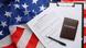 Ein USA Antrag für ein Visum liegt auf der US-Flagge, auf dem weißen Antragsbogen liegen ein dunkler Stift und Passport Ein USA Antrag für ein Visum liegt auf der US-Flagge, auf dem weißen Antragsbogen liegen ein dunkler Stift und Passport