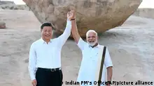 In this Friday, Oct. 11, 2019, handout photo provided by the Indian Prime Minister's Office, Chinese President Xi Jinping and Indian Prime Minister Narendra Modi raise hands together at Arjuna's Penance in Mamallapuram, India. Xi on Friday met with Modi at a time of tensions over Beijing's support for Pakistan in opposing India's downgrading of Kashmir's semi-autonomy and continuing restrictions on the disputed region. (Indian Prime Minister's Office via AP)
