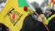 A supporter of Iraq's Hezbollah brigades attends the funeral carrying a Hezbollah flag. A supporter of Iraq's Hezbollah brigades attends the funeral carrying a Hezbollah flag.