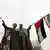 دو تن در اعتراضی در ایران پرچم‌های این کشور و فلسطینی‌ها را اهتزاز می‌دهند