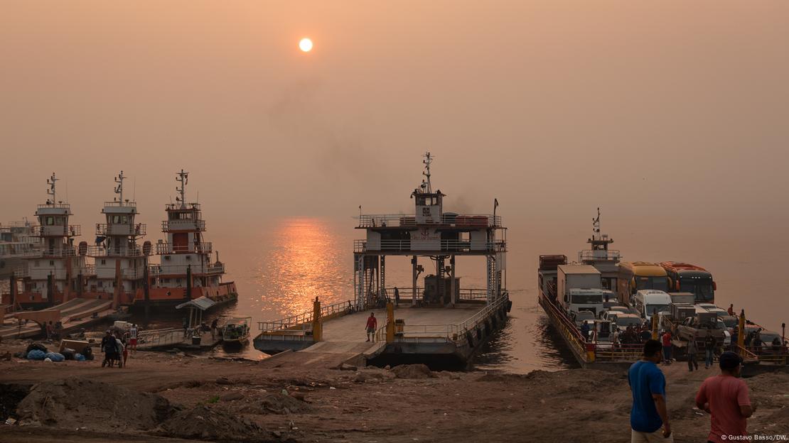 Barcos y sol asomando a través de un cielo gris por el humo. 