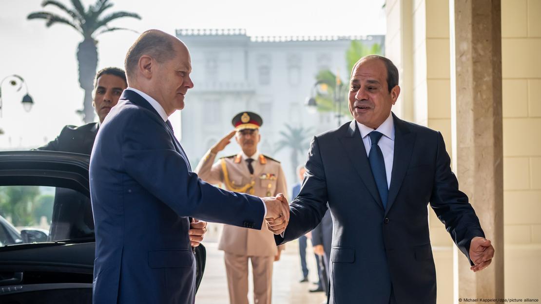 Olaf Scholz aperta mão de Abdel Fattah al-Sisi, com guarda fazendo continência ao fundo