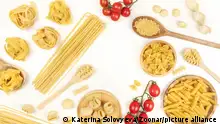 An overhead photo of different types of pasta, including spaghetti, penne, fusilli, and others, with cherry tomatoes, forming a frame, shot from above on a white background with copy space
