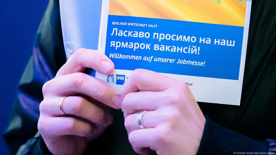 Млад човек държи в ръцете си листовка на германската Агенция по заетостта на украински