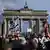 Participants wave Israeli flags at a mass raljy in Berlin in support of Israel and denouncing antisemitism as the Brandenburg Gate features prominently in the background