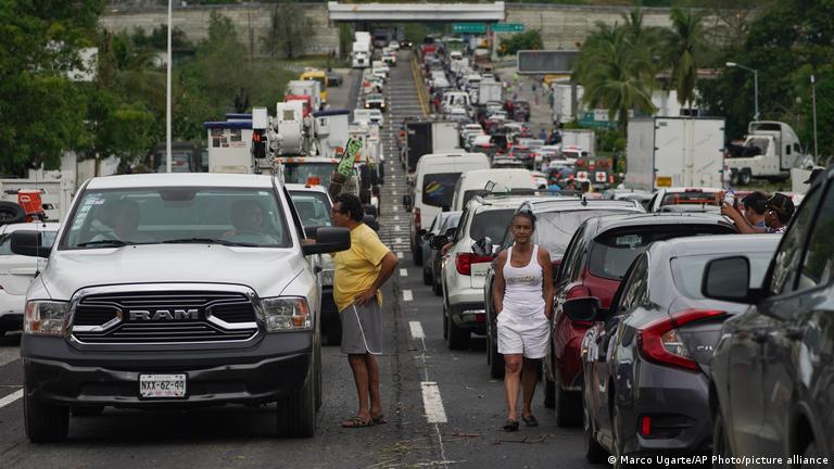 La gente espera afuera de sus automóviles mientras esperan que los equipos de reparación despejen las carreteras tras los estragos ocasionados por el huracán Otis en Acapulco, estado de Guerrero.