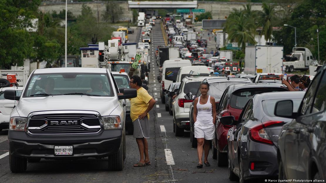 La gente espera afuera de sus automóviles mientras esperan que los equipos de reparación despejen las carreteras tras los estragos ocasionados por el huracán Otis en Acapulco, estado de Guerrero.