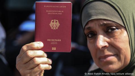 La mujer, ataviada con la ropa tradicional, muestra su pasaporte alemán.