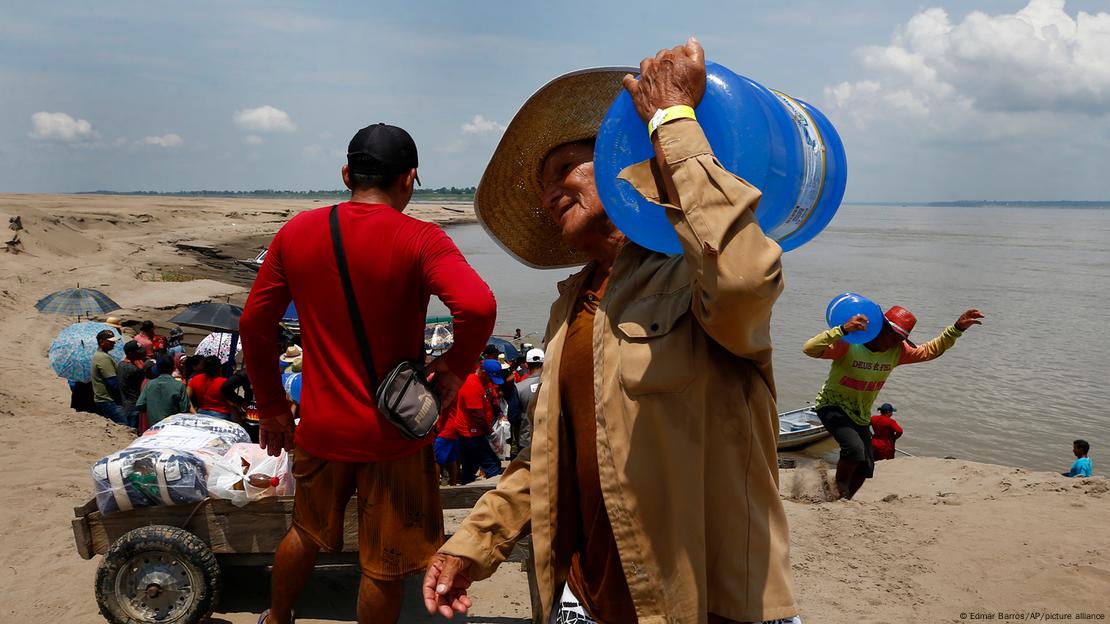 Homens carregando galões de água potável durante seca no estado do Amazonas