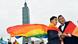 Two men wearing pride flags as capes in front of the Taipei 101 skyscraper Two men wearing pride flags as capes in front of the Taipei 101 skyscraper