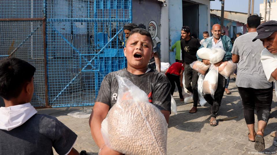 Niños y adultos acarrean sacos de harina y legumbres.