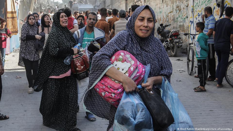 Varias mujeres lloran portando sus pertenencias por una concurrida calle de Rafah.
