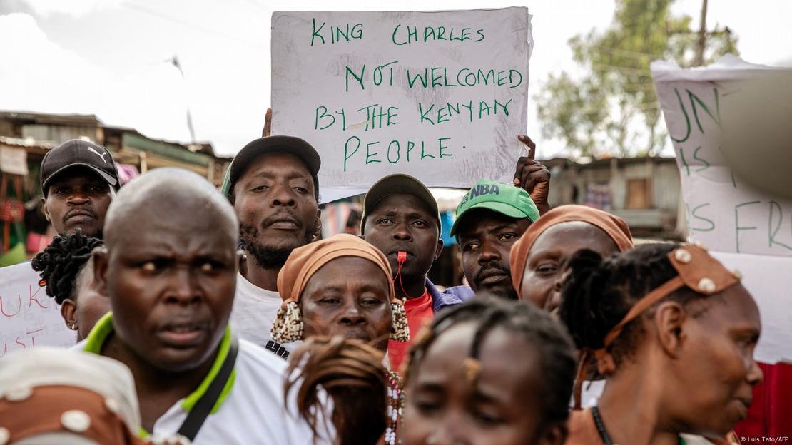 Kenianische Demonstranten protestieren über den Besuch von König Charles III und halten ein weißes Plakat hoch mit der Aufschrift: König Charles ist nicht willkommen