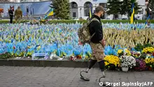 A serviceman, wearing prosthetic legs, walks past the Ukrainian flags symbolising the fallen soldiers on the Independence Square in Kyiv, on October 30, 2023, amid the Russian invasion of Ukraine. (Photo by Sergei SUPINSKY / AFP)