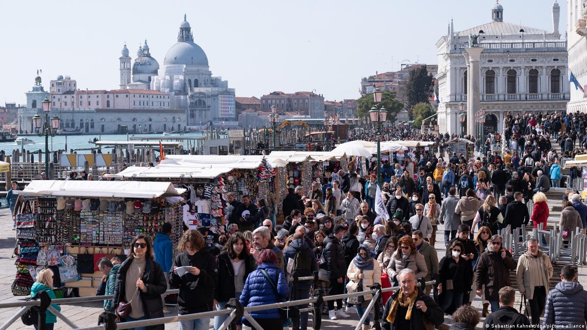 Touristen gehen am Markusplatz in Venedig an zahlreichen Souvenirständen vorbei, Italien