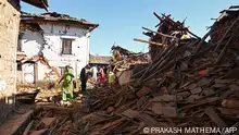 04/11/2023 TOPSHOT - People walk through ruins of houses in the aftermath of an earthquake at Jajarkot district on November 4, 2023. At least 132 people were killed in an overnight earthquake of 5.6-magnitude that struck a remote pocket of Nepal, officials said on November 4, as security forces rushed to assist with rescue efforts. (Photo by Prakash MATHEMA / AFP)