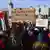 Manifestante exibe cartaz em manifestação com a frase "Do rio ao mar, palestina será livre" em inglês