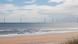 Praia com turbinas eólicas em alto-mar Praia com turbinas eólicas em alto-mar