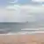 Praia com turbinas eólicas em alto-mar
