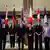 Ministros y ministras posando de pie ante varias banderas.