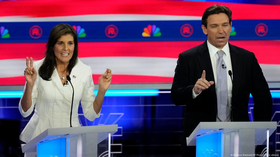 Os republicanos Nikki Haley (esquerda) e Ron DeSantis falam e gesticulam diante de púlpitos durante debate televisionado em novembro de 2023.