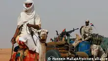 A Sudanese soldiers from the Rapid Support Forces unit which led by Gen. Mohammed Hamdan Dagalo, the deputy head of the military council, sits on his vehicle as a man rides a camel passes next of him, during a military-backed tribe's rally, in the East Nile province, Sudan, Saturday, June 22, 2019. Sudan's protest leaders say they are meeting with an Ethiopian envoy over proposals to resume negotiations with the ruling military council. (AP Photo/Hussein Malla)