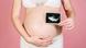 A pregnant woman holding up an ultrasound photo next to her stomach A pregnant woman holding up an ultrasound photo next to her stomach