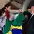Lula cumprimenta duas jovens, que usam lenços palestinos e seguram uma bandeira do Brasil