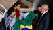 Duas meninas com a bandeira do Brasil são recebidas por Lula na saída de um avião.