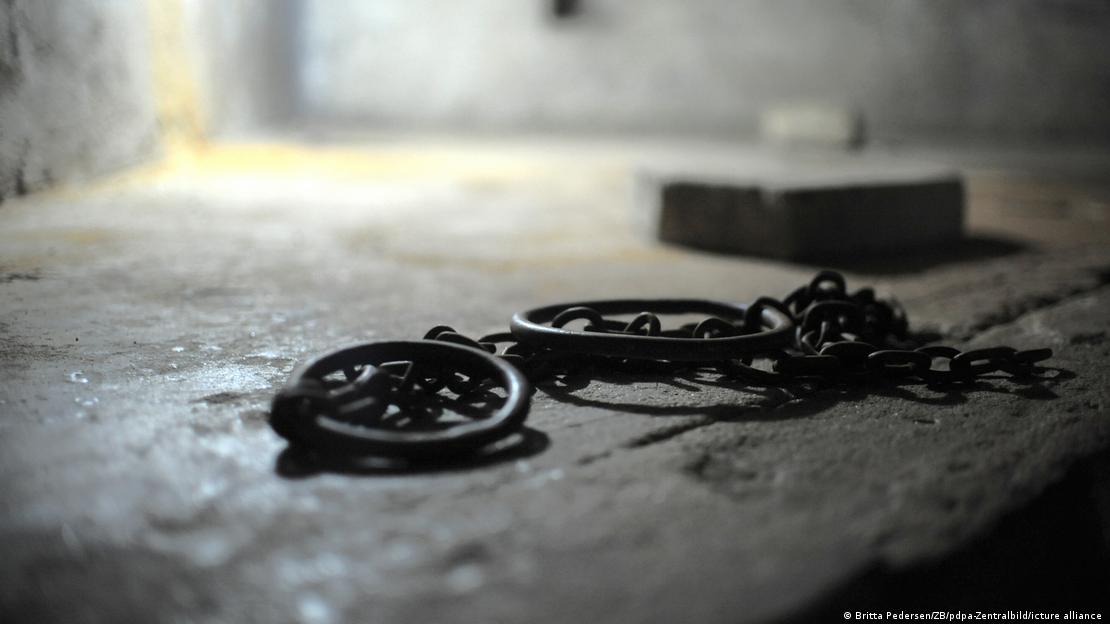 Nahaufnahme von antiken Fußfesseln mit Eisenkette auf Steinboden