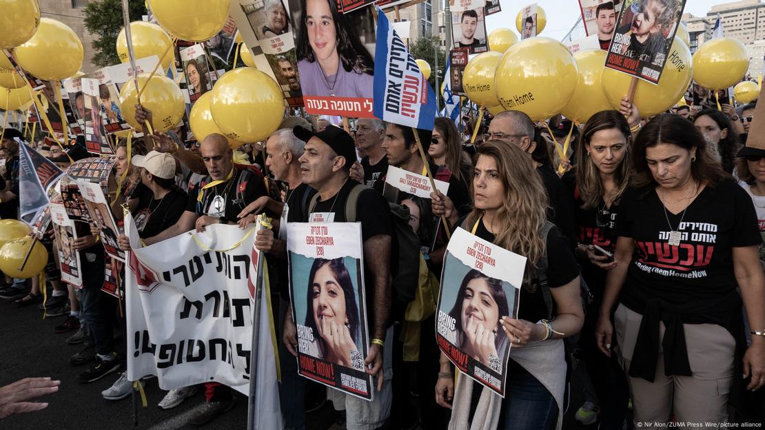 Pessoas carregam faixas e cartazas com fotos de pessoas em passeata