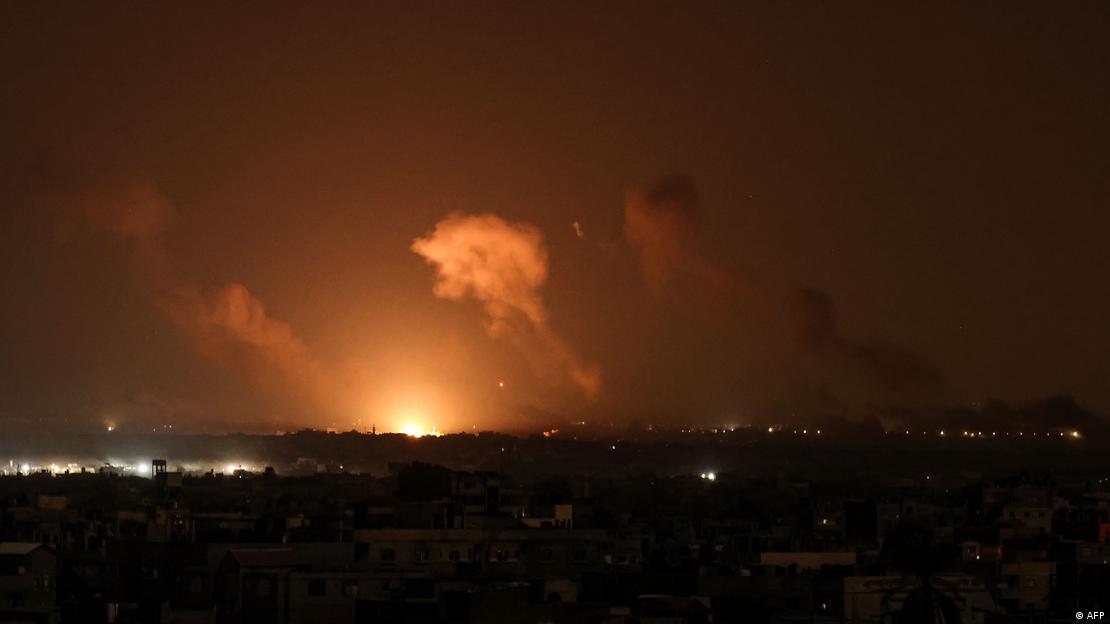 Imagem noturna mostra explosão e fumaça no horizonte de cidade Imagem noturna mostra explosão e fumaça no horizonte de cidade
