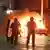 Polizisten in Schutzkleidung vor einem brennenden Auto in Dublin