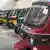 A row of shiny new red, green, yellow and blue tuk-tuks line the inside of a warehouse