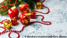 Christmas decorations in the form of apples, fir branch and red garland-beads on a light background