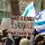 Protesters hold up a sign reading "Believe Israeli women" and the Israeli flag